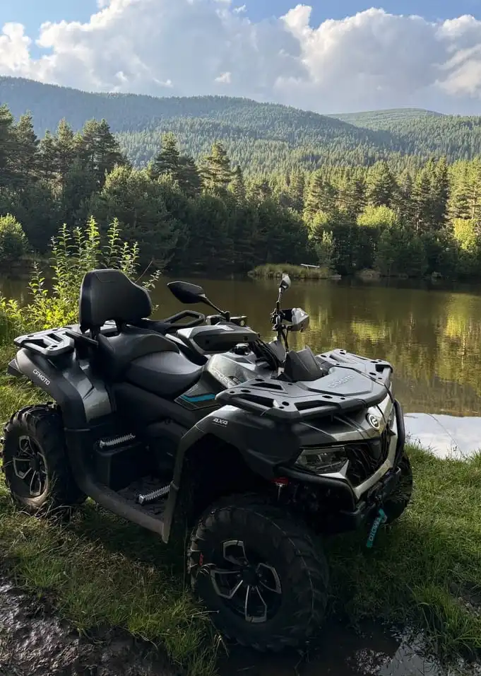 Two 2026 CFMOTO 625 quads on a forest track in the Pirin Mountains above Bansko, Bulgaria